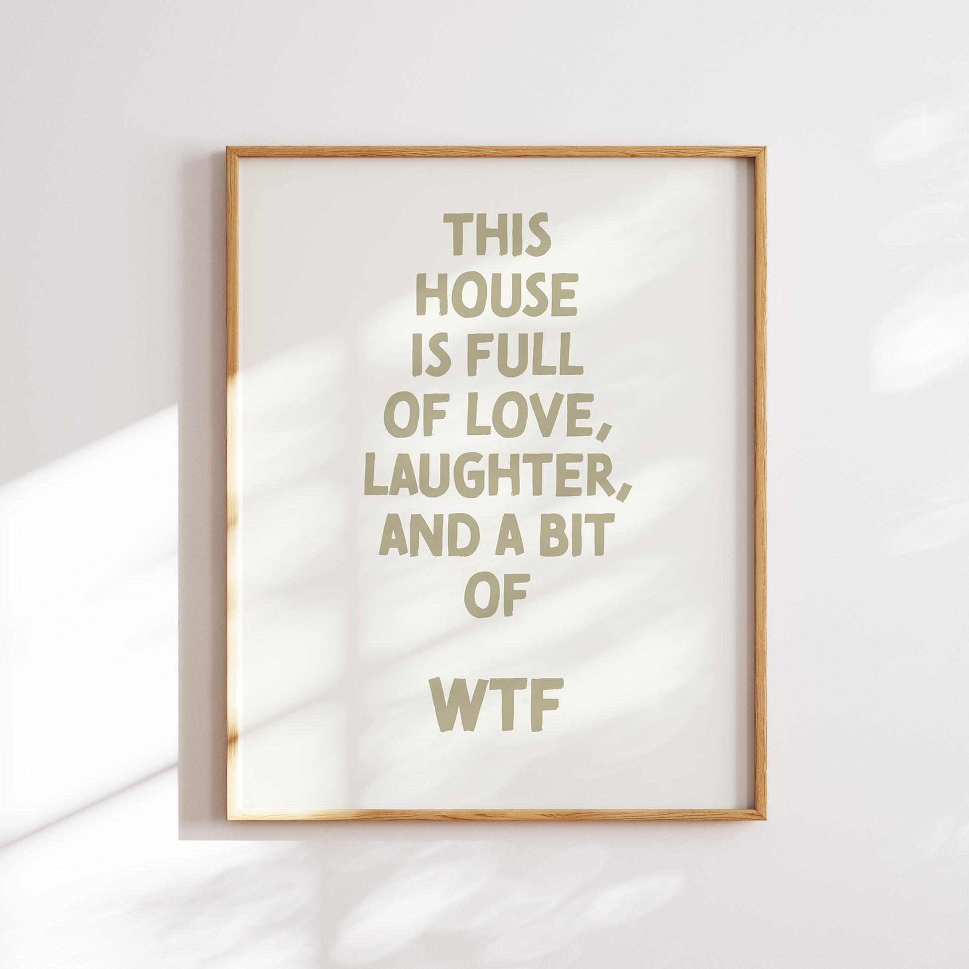 Trendy printable wall art poster featuring a  ""This house is full of love, laughter and a bit of wtf"" text in a stylish cream and boho olive green design. Perfect for adding a touch of cool humor to any room or as a unique gift. Instantly downloadable.
Shop unique wall art now by WonkyWonder.